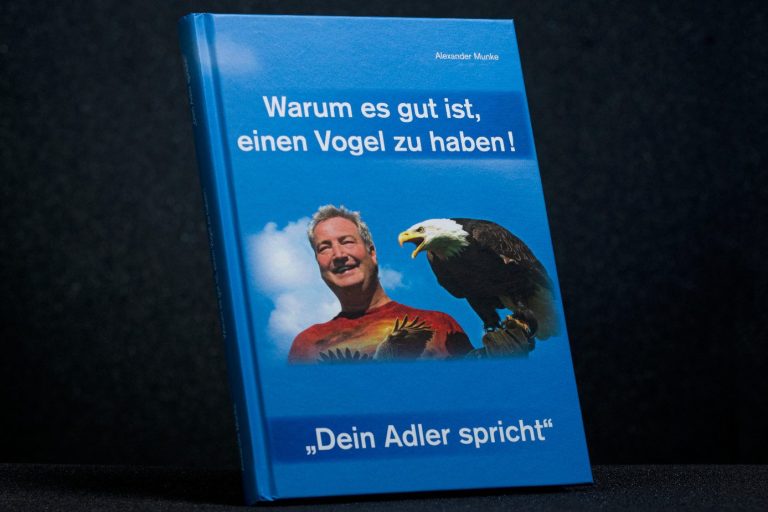 Das Buch hat einen blauen Einband. Auf ihm ist Alexander Munke mit einem echten Weißkopfseeadler auf der Hand zu sehen.